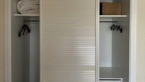A walk-in closet with a large sliding door, shelves, and hanging storage.