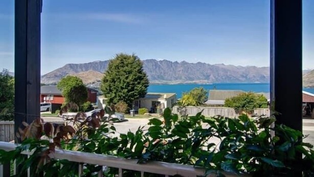 A view from a balcony overlooking a mountain range and a body of water.