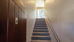 A carpeted staircase with a handrail, wooden paneling on one side, and a door labeled 'A' at the bottom.