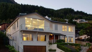 A modern two-story house with a large balcony, a garage, and a well-maintained garden.