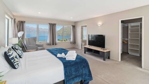 A hotel room with a bed, a TV, a seating area with a view, and a walk-in closet.