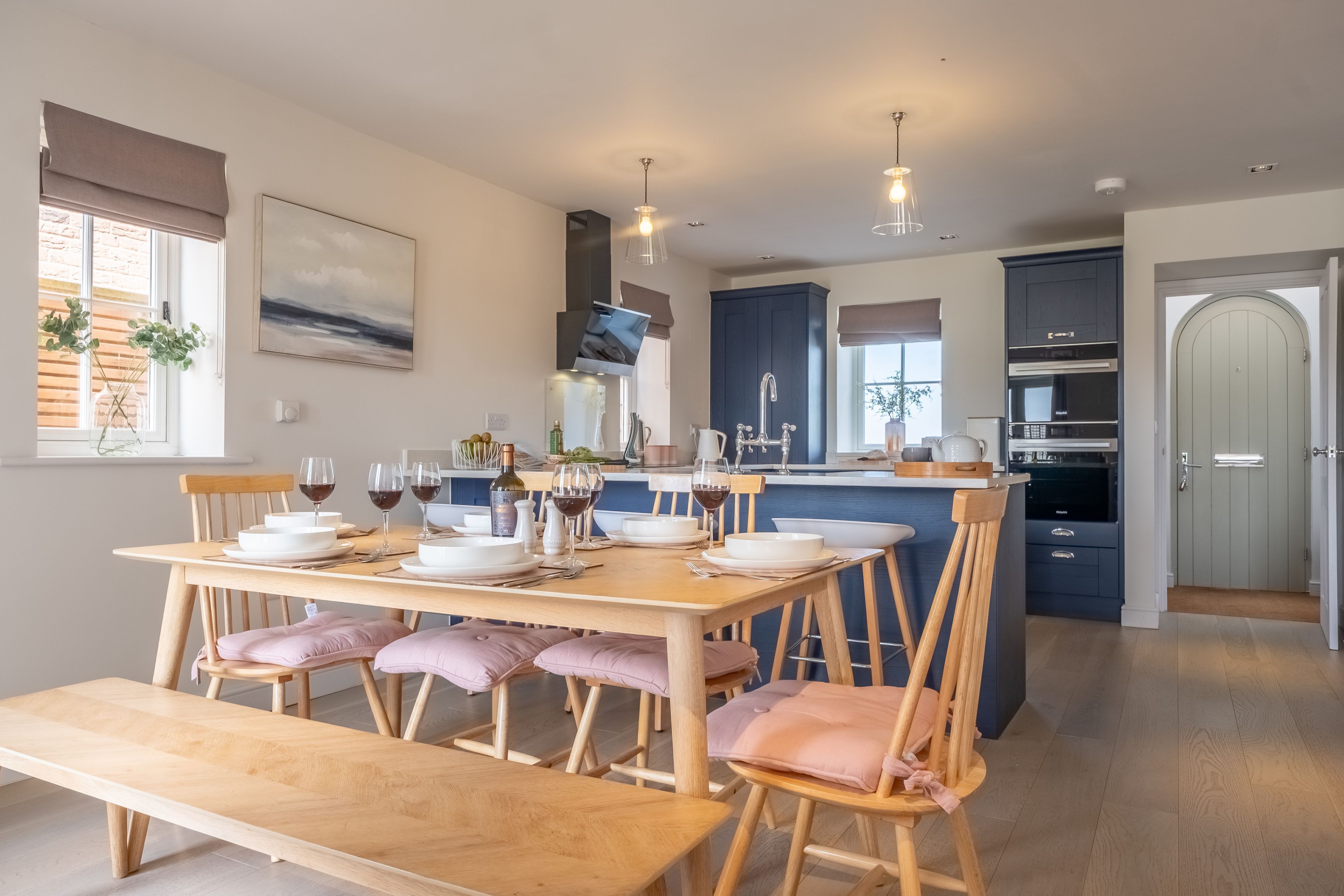 Een moderne keuken met een eethoek, houten meubels en uitzicht op buiten.