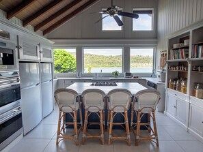 Een keuken met een groot kookeiland, witte kasten en uitzicht op de omgeving.