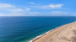 A beach with clear blue water and a sandy shore.