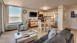 Eine moderne Wohnung mit Wohnzimmer, Essbereich, Küche und einem großen Fenster mit Blick.