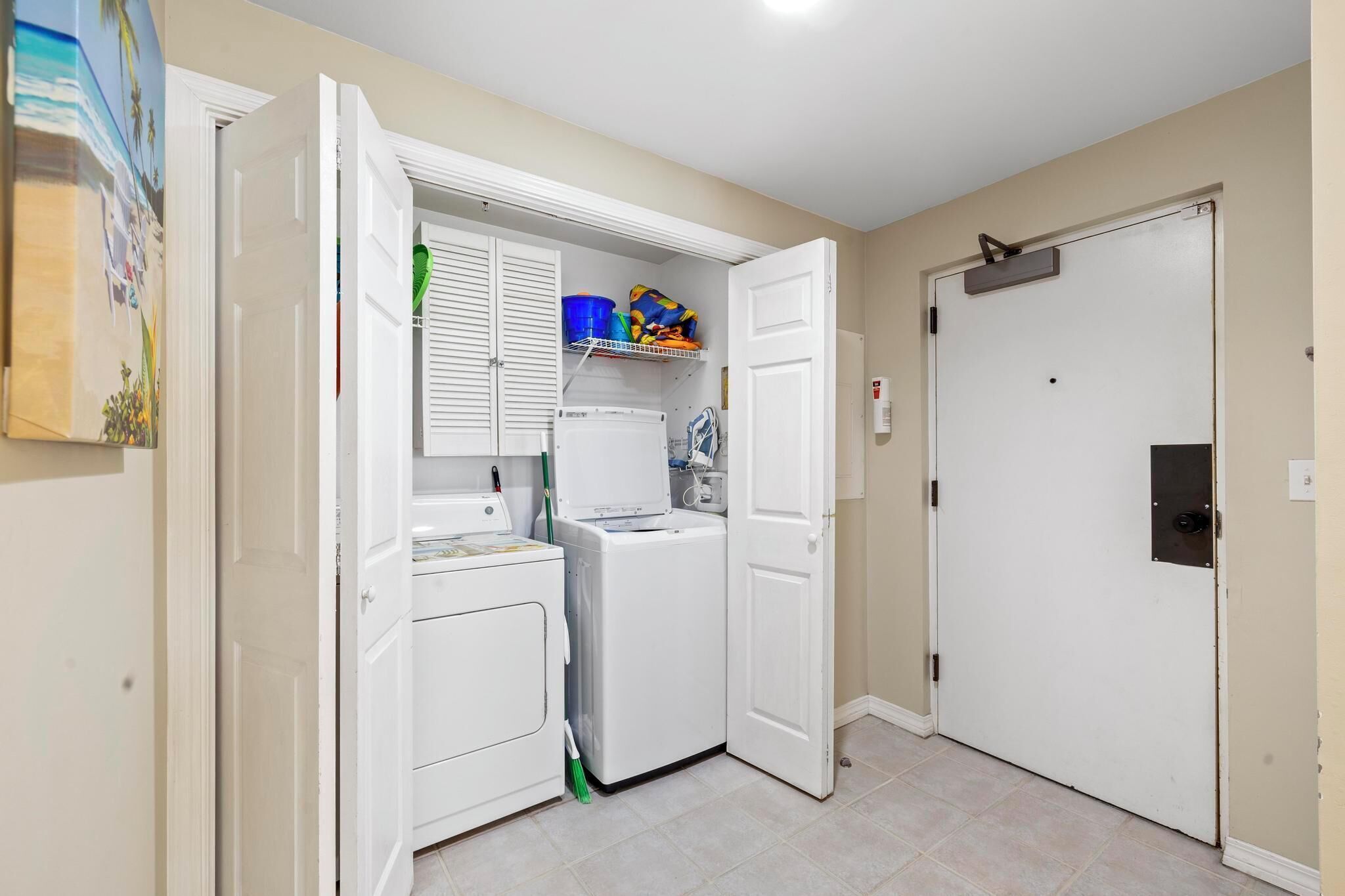 A laundry room with a washing machine, dryer, and shelves with cleaning supplies.