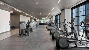 Ein Fitnessraum mit Laufbändern und Kraftgeräten, die in Reihen angeordnet sind.