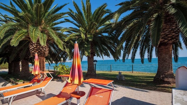 A beachside lounge area with sun loungers and umbrellas, palm trees, and a view of the sea. - Villa Lucia - Bilo 4 Mandarin - ground floor (Puglia)
