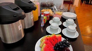 Un bufé de desayuno con máquinas de café, zumos, cereales y fruta.