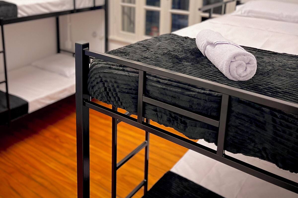 A dormitory room with bunk beds, a window with a view, and a door.