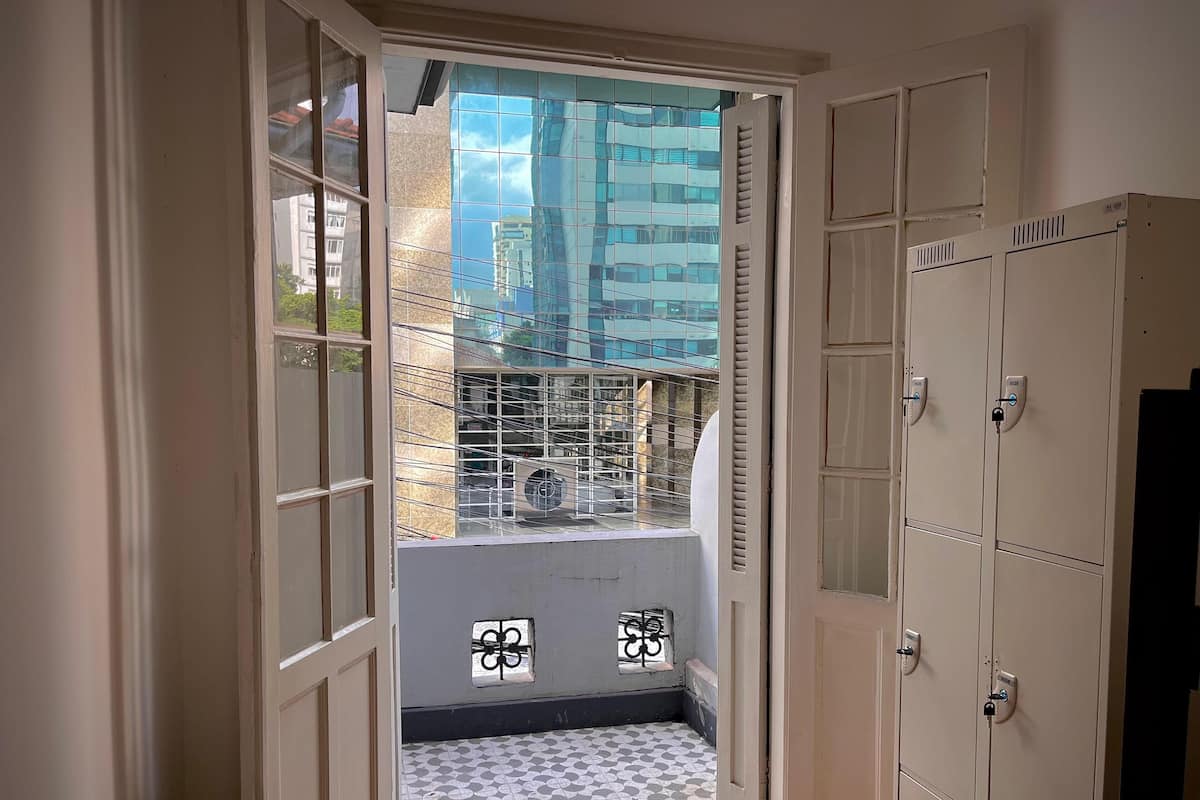 A narrow hallway with a glass door leading to a balcony with a patterned floor and metal railing.
