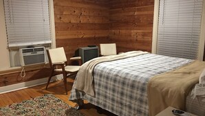 A bedroom with a bed, a chair, a television, and a window with blinds. - Desirable Elmwood location. Tudor style garage apt studio w/central heat& a/c. (Abilene)