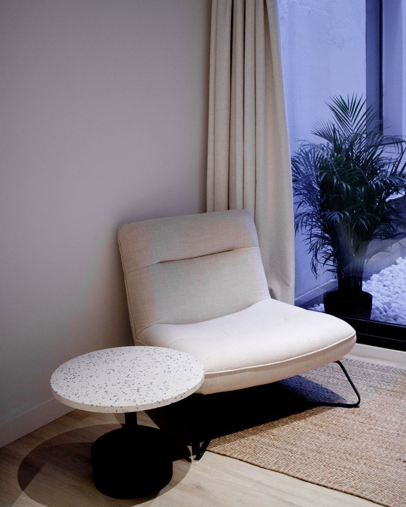 A corner seating area with a cushioned chair, a small round table, and a potted plant.