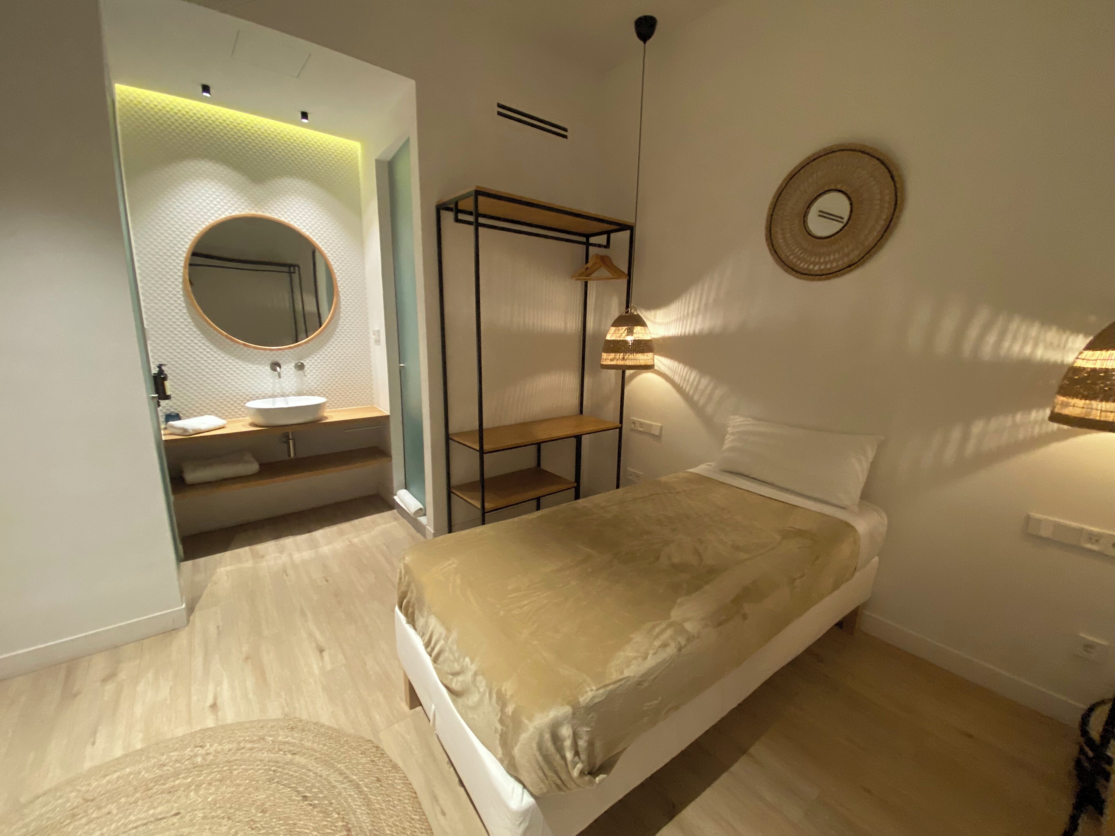 Ein modernes Schlafzimmer mit einem Bett, einem Nachttisch, einer Pendelleuchte, einem Spiegel und einer Regaleinheit.