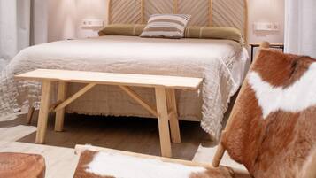 Un dormitorio con cama de madera, dos lámparas de noche, un tapiz en la pared y una silla marrón y blanca.