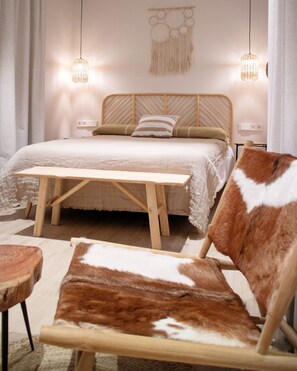 A bedroom with a wooden bed, two bedside lamps, a wall hanging, and a brown and white chair. - Casa du Soleil Hostal Boutique (Madrid)