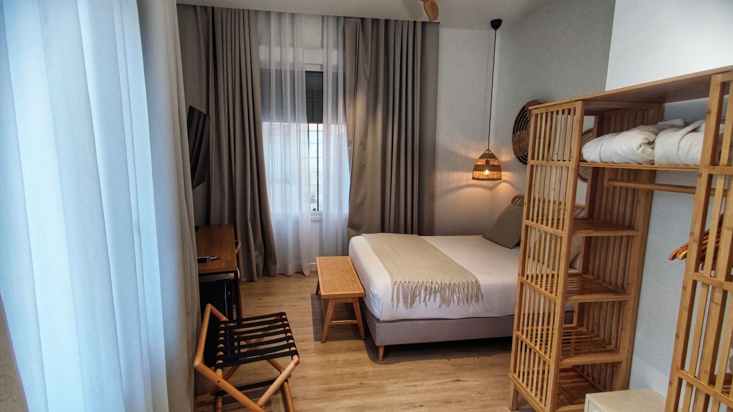 A bedroom with a bed, wooden furniture, a desk, and a chair.