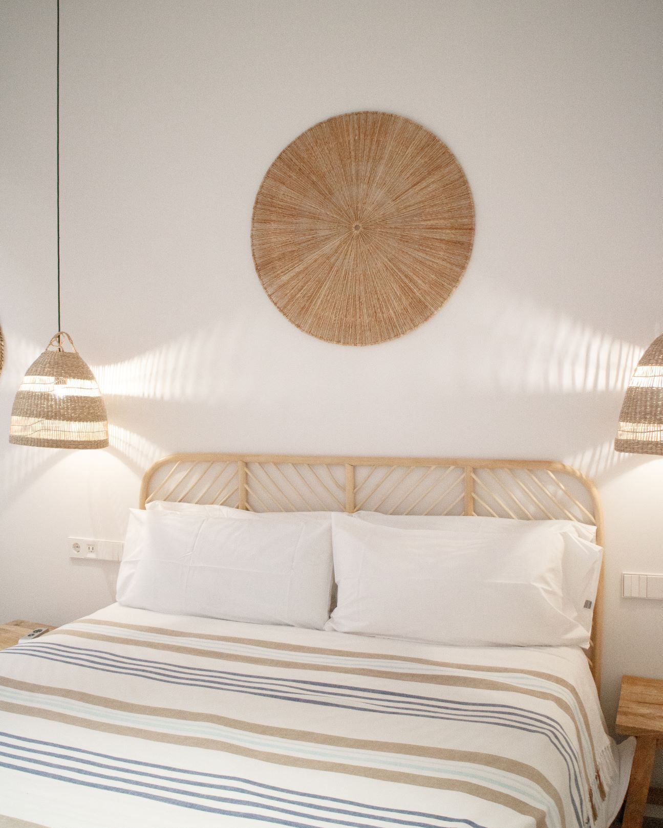 Un dormitorio con cama, dos lámparas de noche y un adorno circular en la pared.