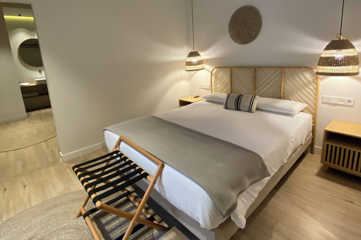 A modern bedroom with a wooden bed, a ceiling fan, and a circular wall decoration.