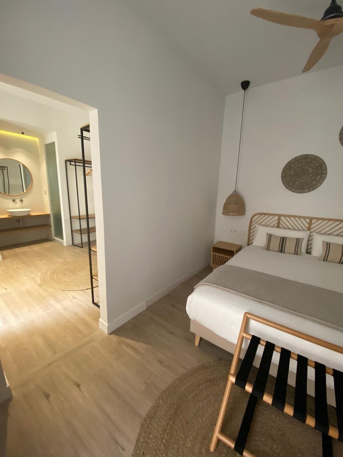Un dormitorio con cama, mesita de noche, lámpara colgante y ventilador de techo.