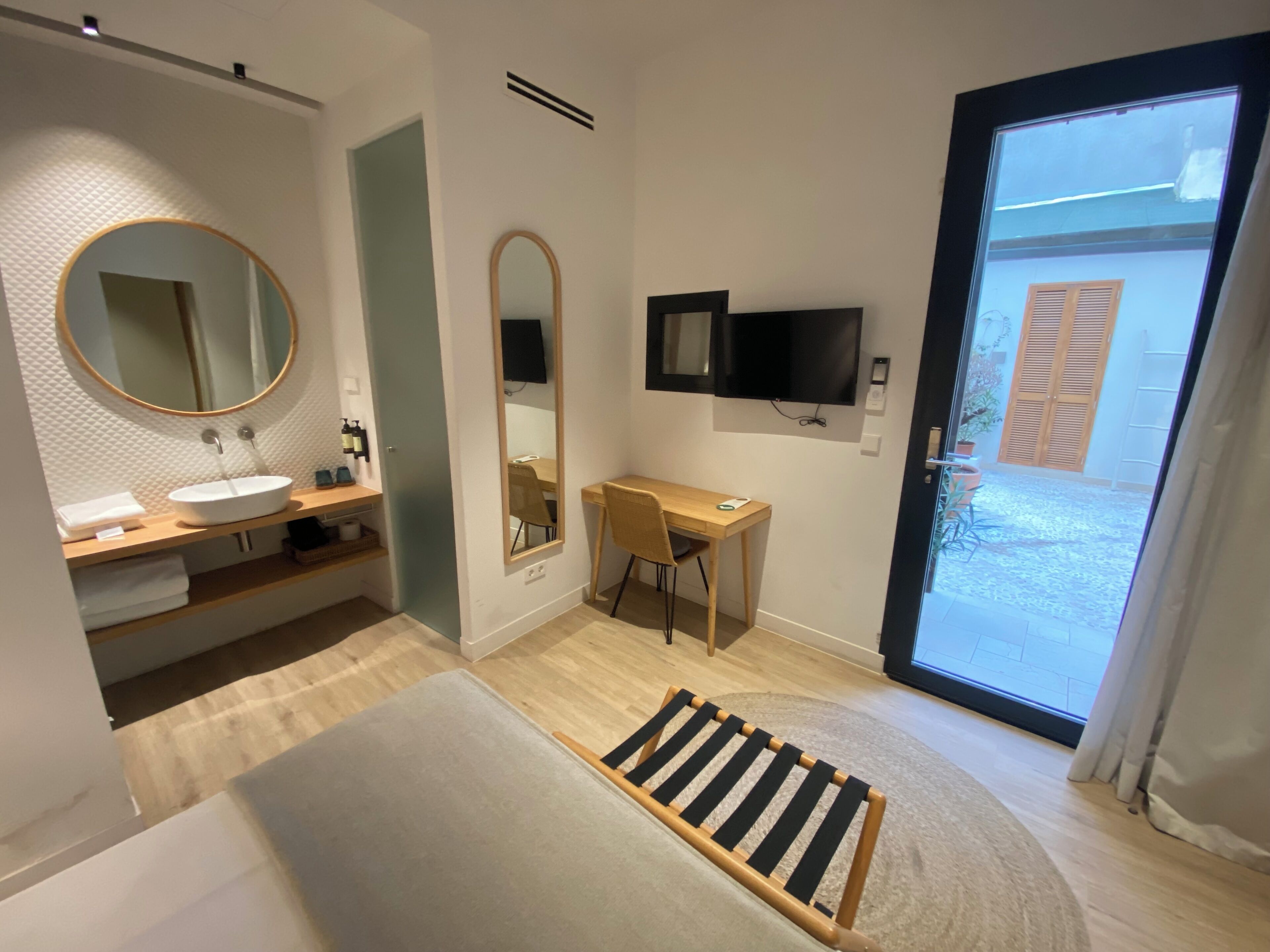 A modern bathroom with a round mirror, a sink, and a wooden desk.