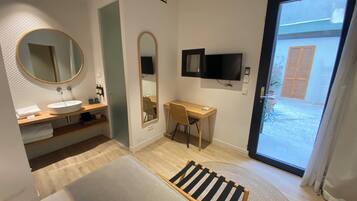 A modern bathroom with a round mirror, a sink, and a wooden desk.