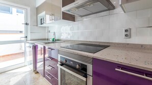 A modern kitchen with a built-in oven, a stainless steel range hood, and a large window.