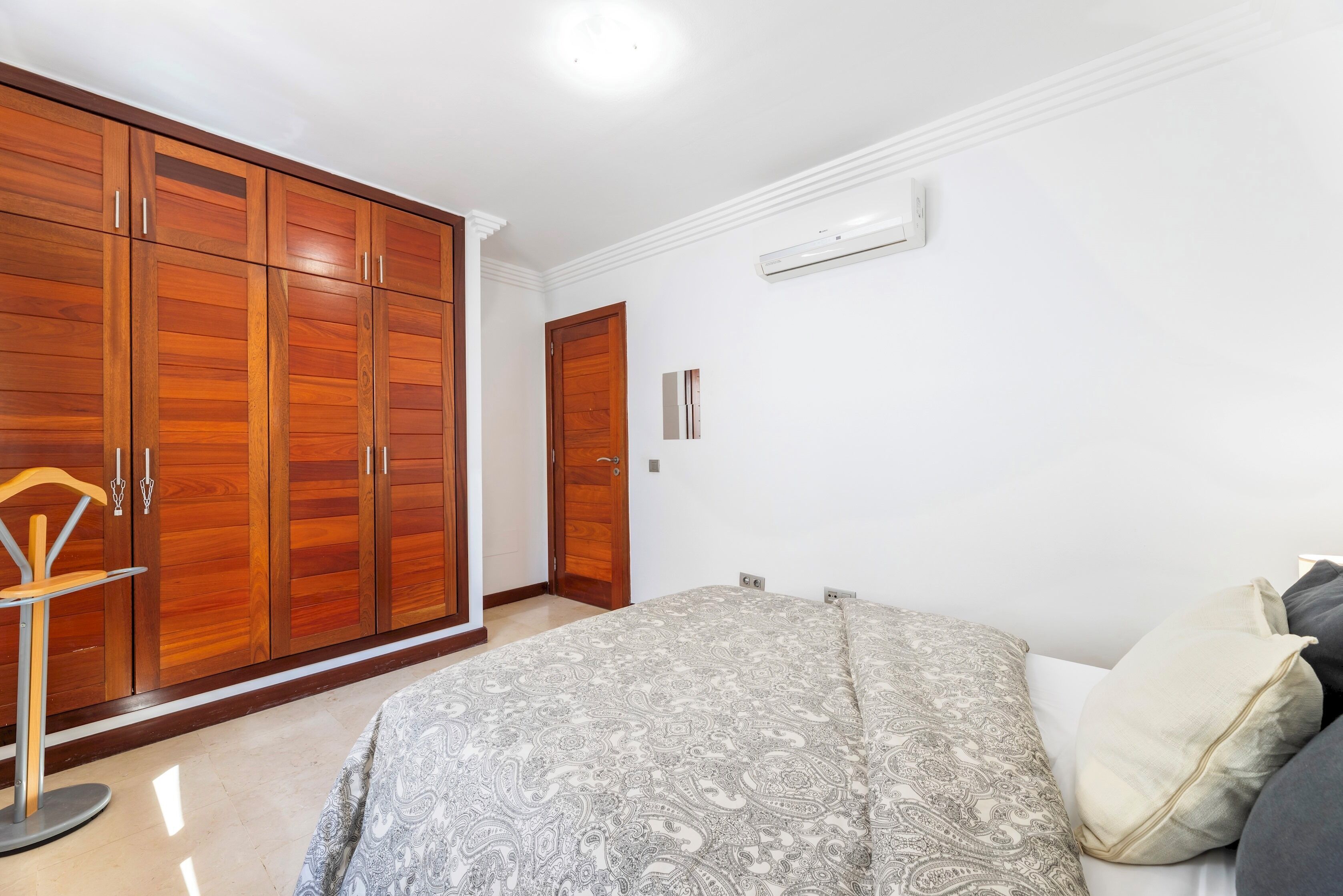 A bedroom with a bed, a wardrobe, and a chair.