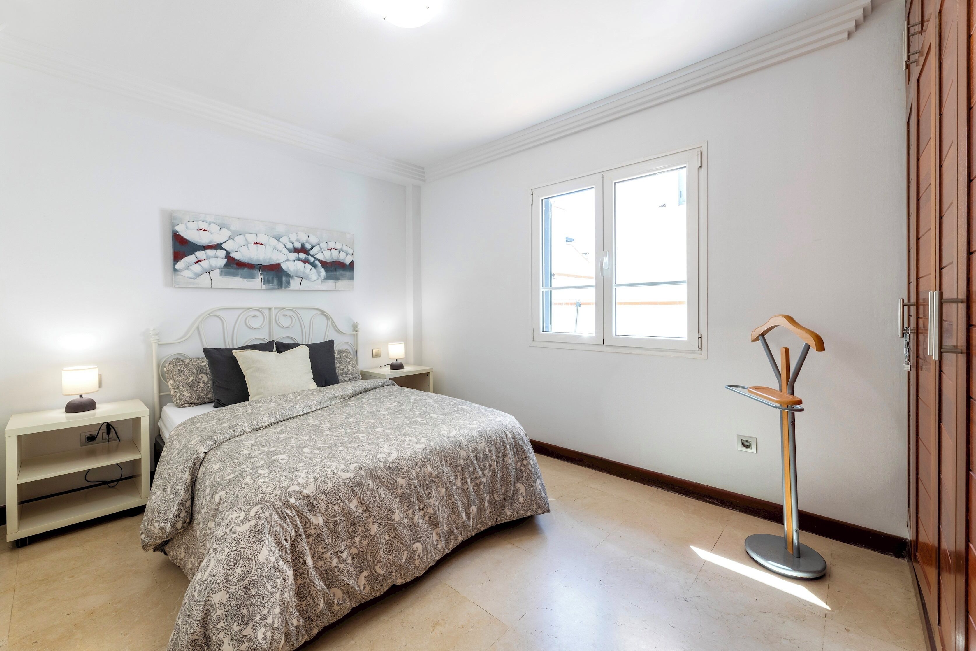 Ein Schlafzimmer mit einem Bett, Nachttischen, einer Stehlampe und einem Fenster.