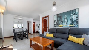 A modern living room with a dark grey sofa, wooden coffee table, and a cityscape painting on the wall.