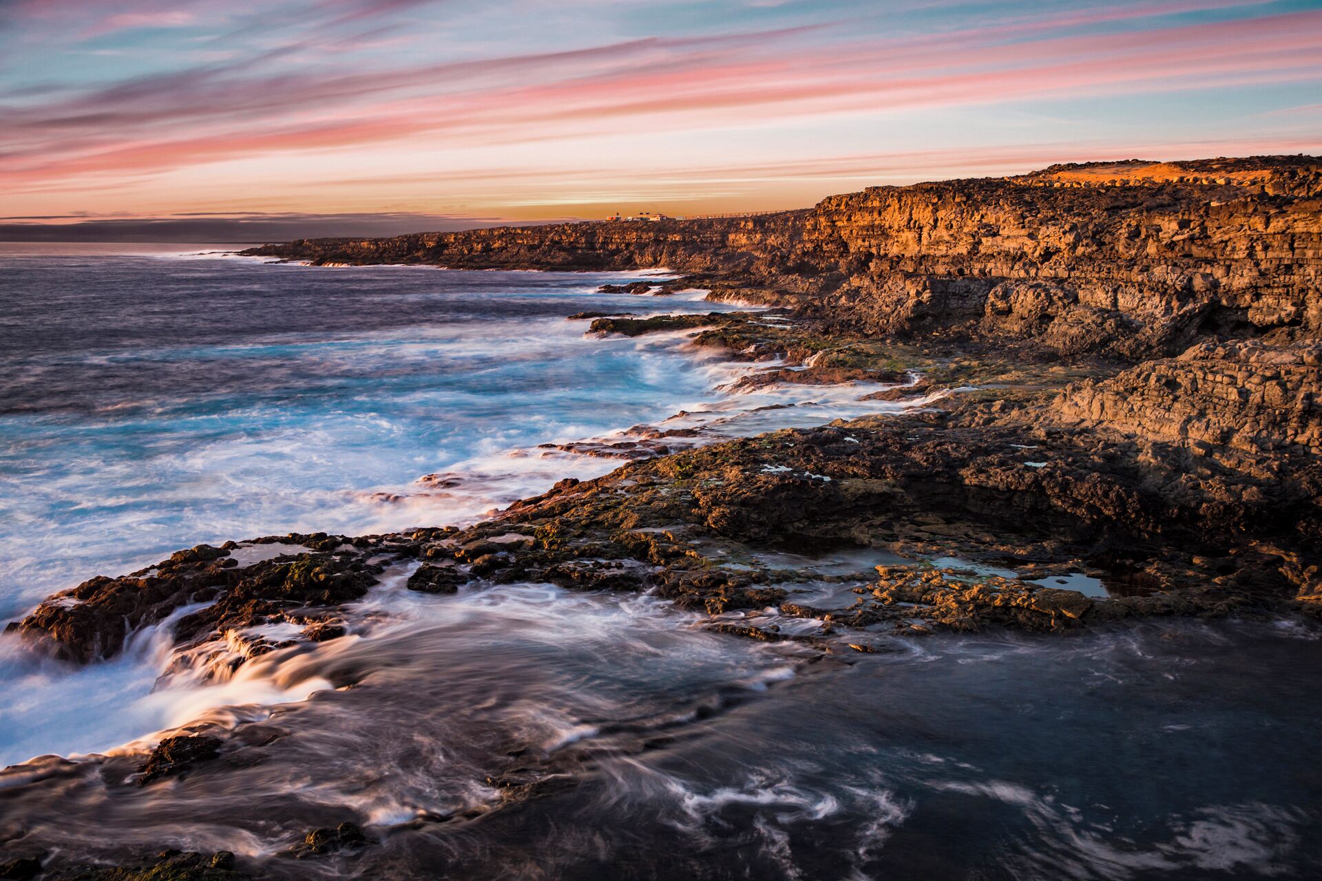 A coastal landscape with rocky cliffs and waves crashing against the shore.