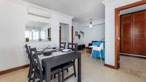 A dining area with a dark wooden table set for four, white walls, and a wooden door in the background.