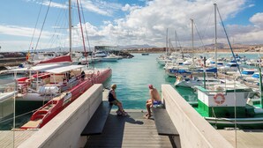 Un port de plaisance avec des bateaux amarrés, une passerelle en bois et un ciel dégagé.