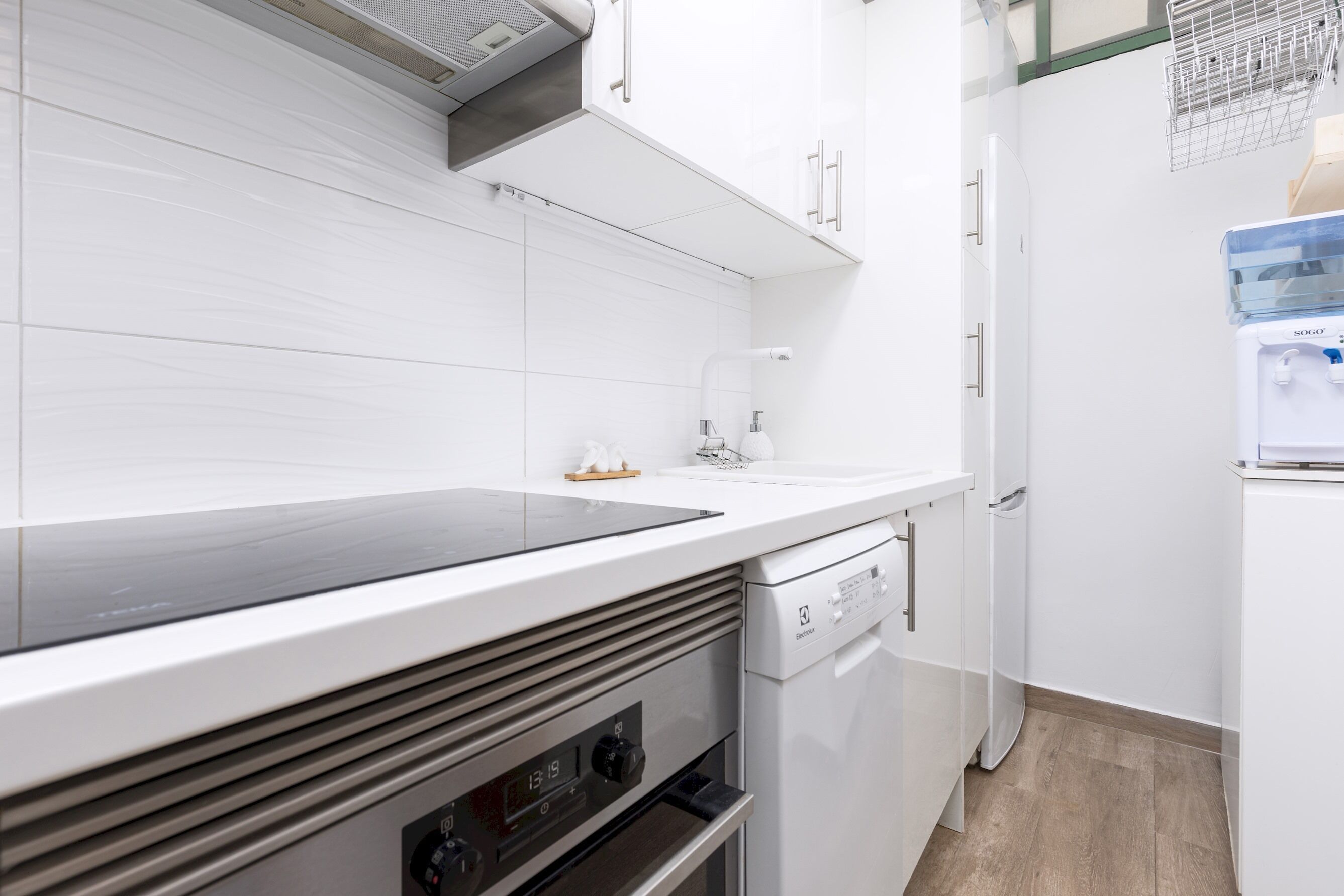 Une cuisine moderne avec des meubles blancs, un four encastré et un lave-vaisselle.