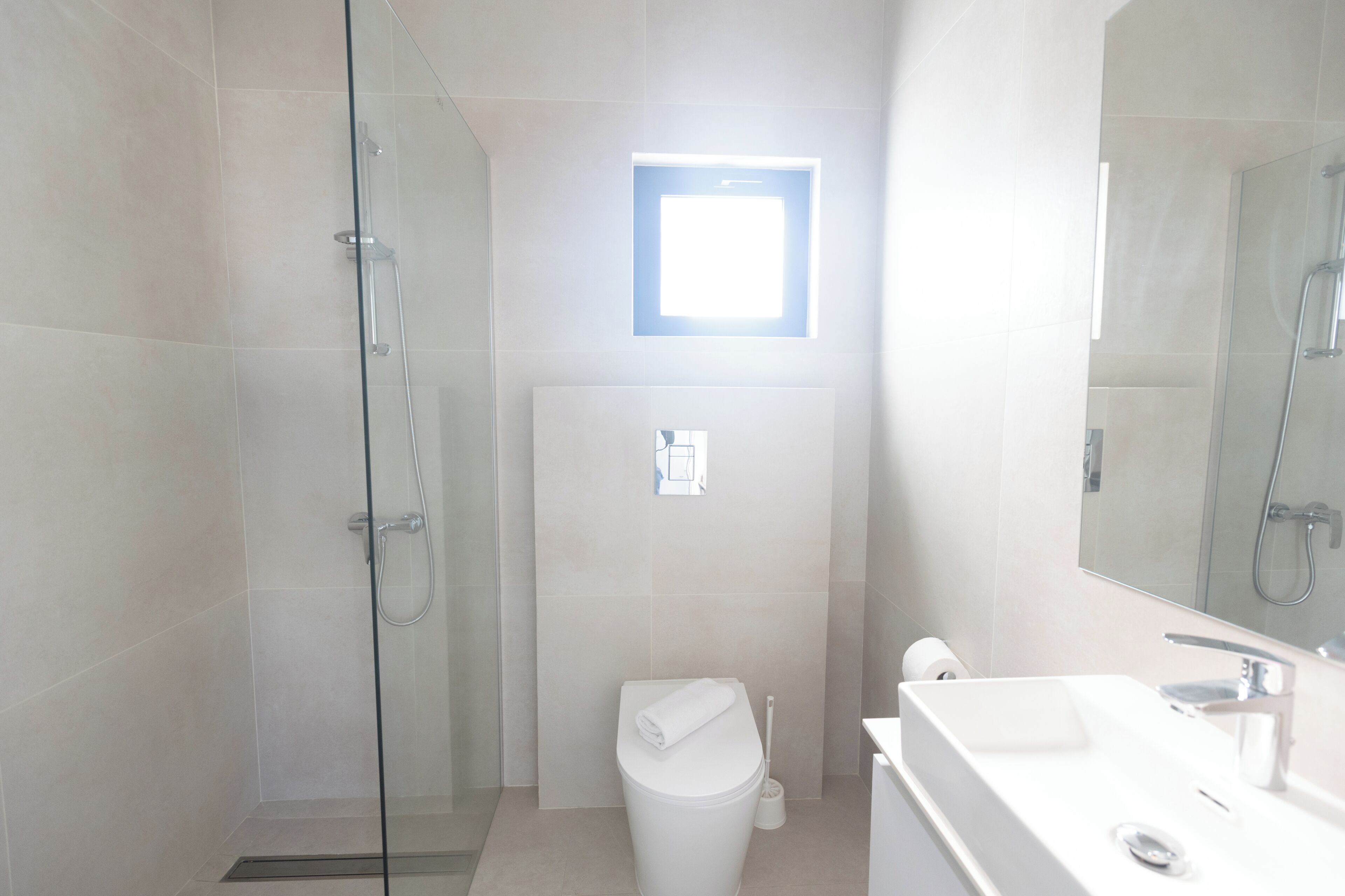 Ein modernes Badezimmer mit Duschkabine aus Glas, Toilette und Waschbecken mit Spiegel.