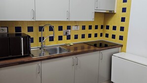 A modern kitchen with grey cabinets, a wooden countertop, a sink, and a microwave. - Cinqueterrehouse (La Spezia)