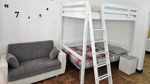 A bunk bed with a ladder, a gray sofa, and a wall clock. - Cinqueterrehouse (La Spezia)