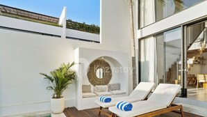 Un área de piscina moderna al aire libre con sillones de descanso y una planta en maceta.