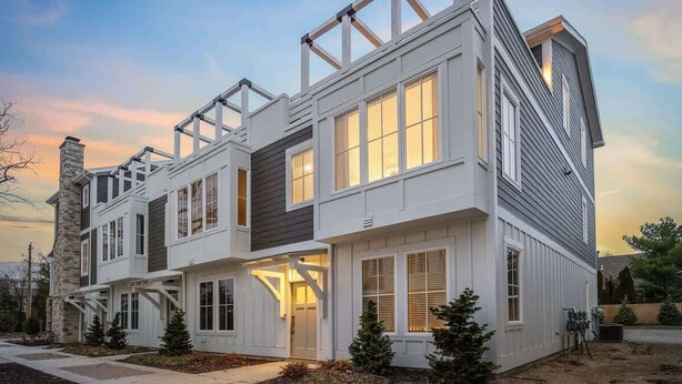 A modern multi-story residential building with a prominent gable roof, large windows, and a stone chimney. - Juniper Presents: Beach Bliss Home with Rooftop Deck & Pool Access (Union Pier)