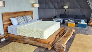 Un hébergement spacieux sous tente, comprenant un lit en bois, un canapé et une petite table.