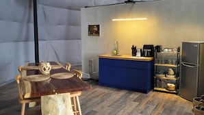 Une cuisine compacte avec un coin repas, comprenant une table en bois, des chaises et un meuble bleu.