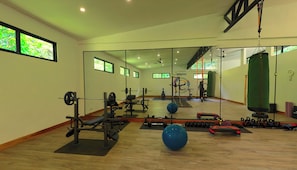 A gym with exercise equipment, a large mirror, and wooden flooring.