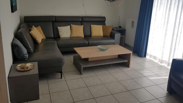Una sala moderna con un sofá modular, una mesa de centro y una mesita auxiliar con un cuenco.