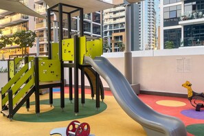A children's play area with a slide, climbing structures, and a giraffe toy. - Upscale Studio Azizi Riviera Prime Location Dubai (Dubai)