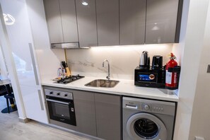 A compact kitchen with a built-in oven, a dishwasher, a sink, and a coffee maker.