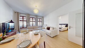A modern living room with a dining area, large windows, and a view of buildings. - Hallebardes Cathédrale (Strasbourg)