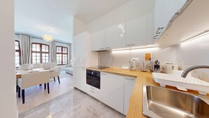 A modern kitchen with white cabinetry, a wooden countertop, and stainless steel appliances. - Hallebardes Cathédrale (Strasbourg)