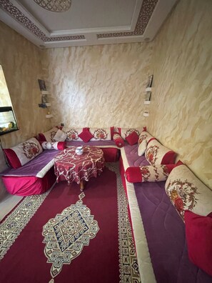 A room with a sofa set, a patterned rug, and a small table with a teapot.