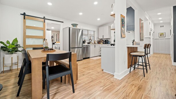 Una cocina moderna con armarios blancos, electrodomésticos de acero inoxidable y una mesa de comedor de madera con sillas.