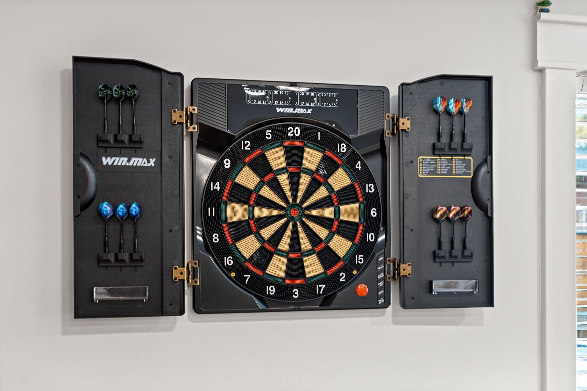 Un jeu de fléchettes avec trois supports à fléchettes, chacun contenant trois fléchettes, fixé au mur.